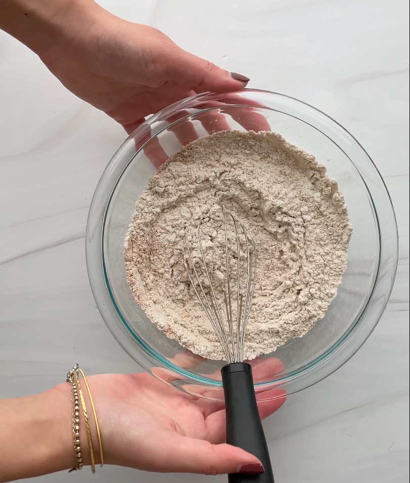 Dry ingredients with a whisk in a glass bowl.