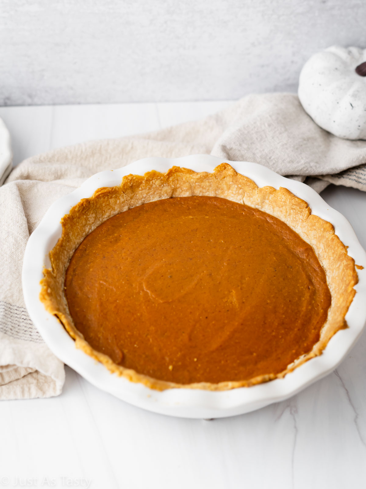 Pumpkin pie in a white pie plate. 