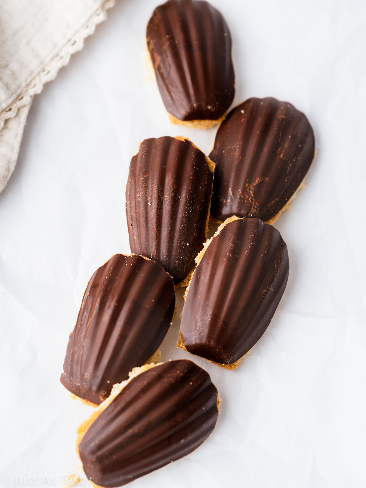 Chocolate dipped madeleines on a white surface. 