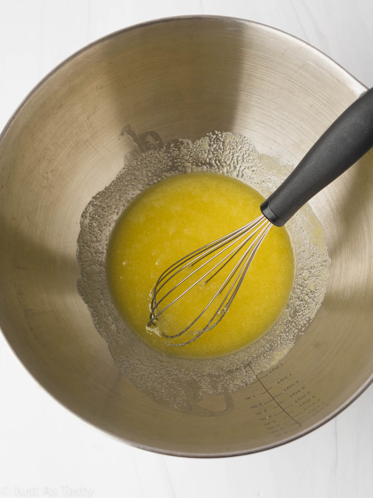 Olive oil and sugar mixture in a bowl with a whisk.