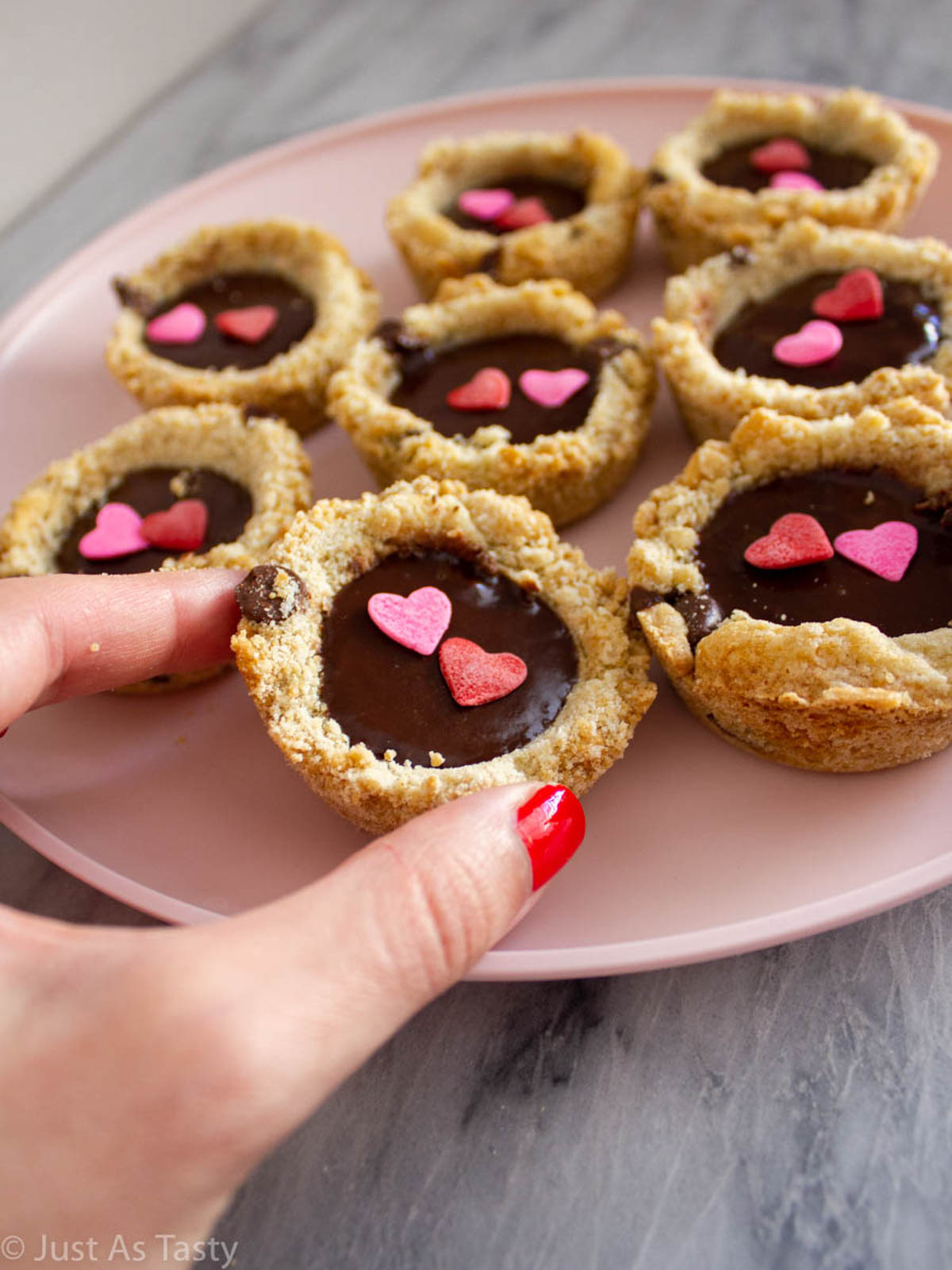 Chocolate chip cookies filled with ganache on a pink plate.