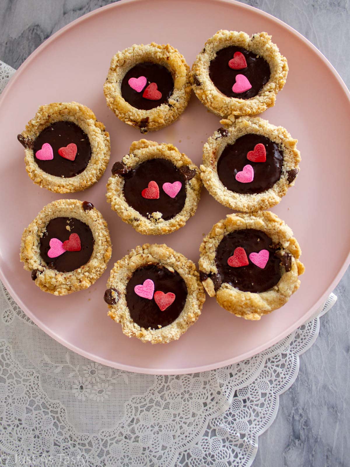 Chocolate chip cookie cups filled with chocolate ganache on a pink plate.