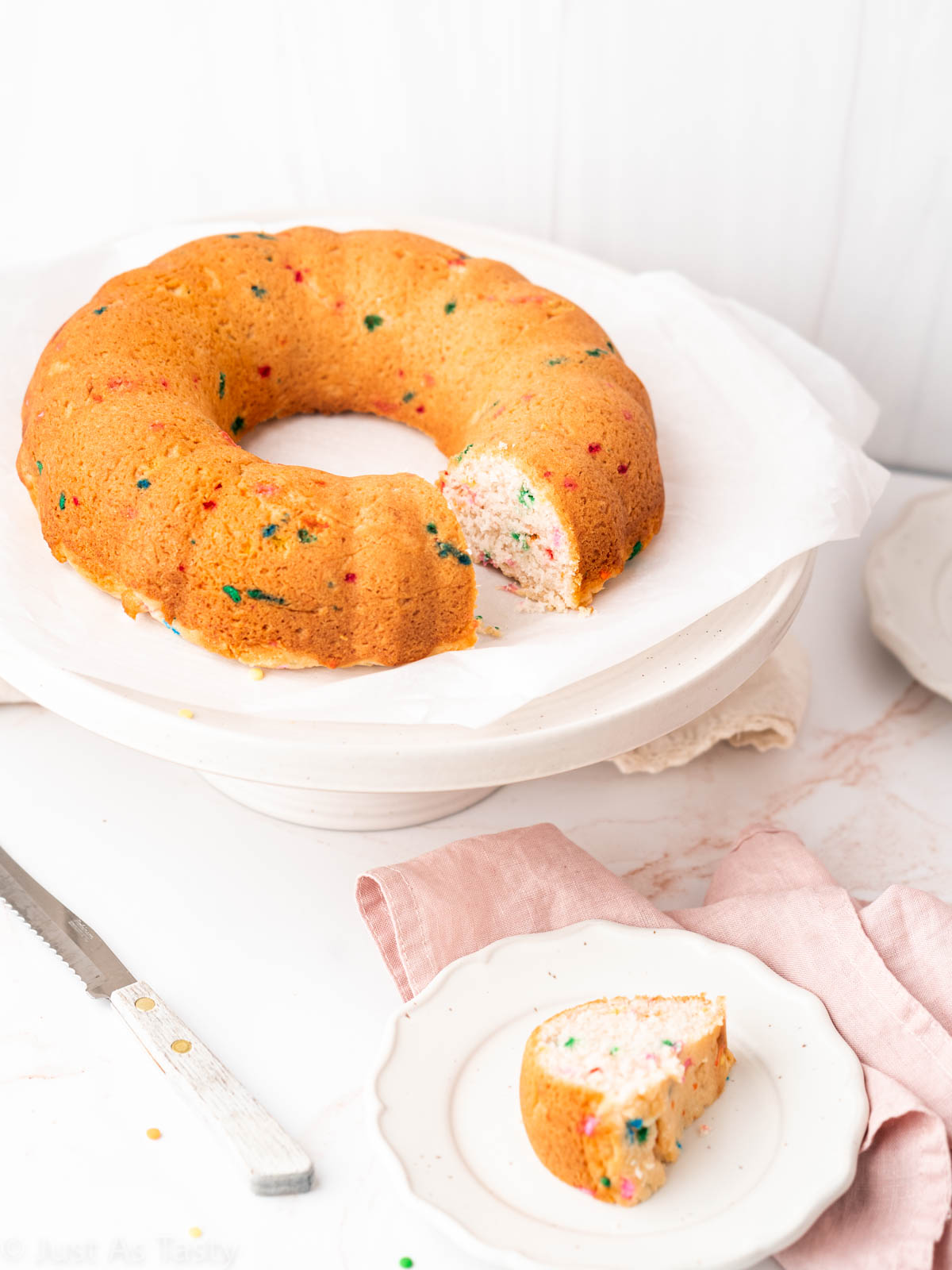 Sliced Bundt cake on a cake stand alongside a slice of cake on a plate. 