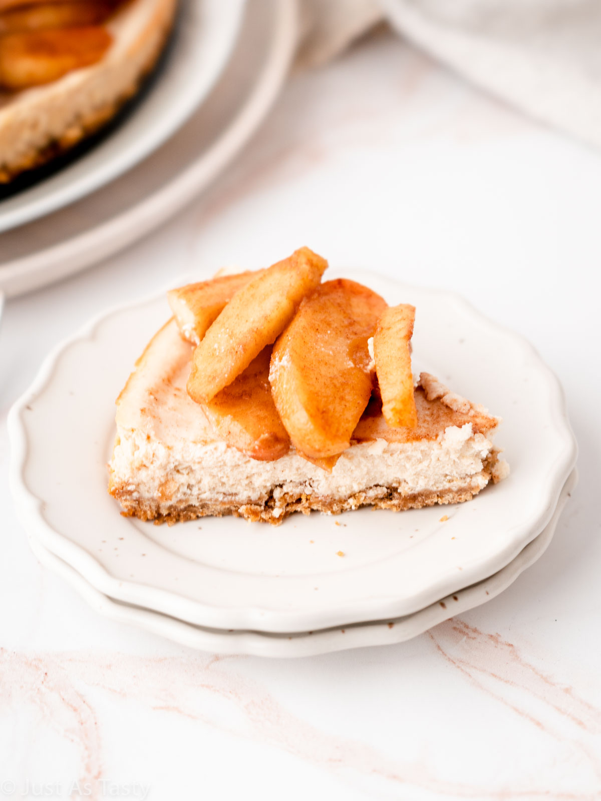 Close-up of an apple pie cheesecake slice on a plate.