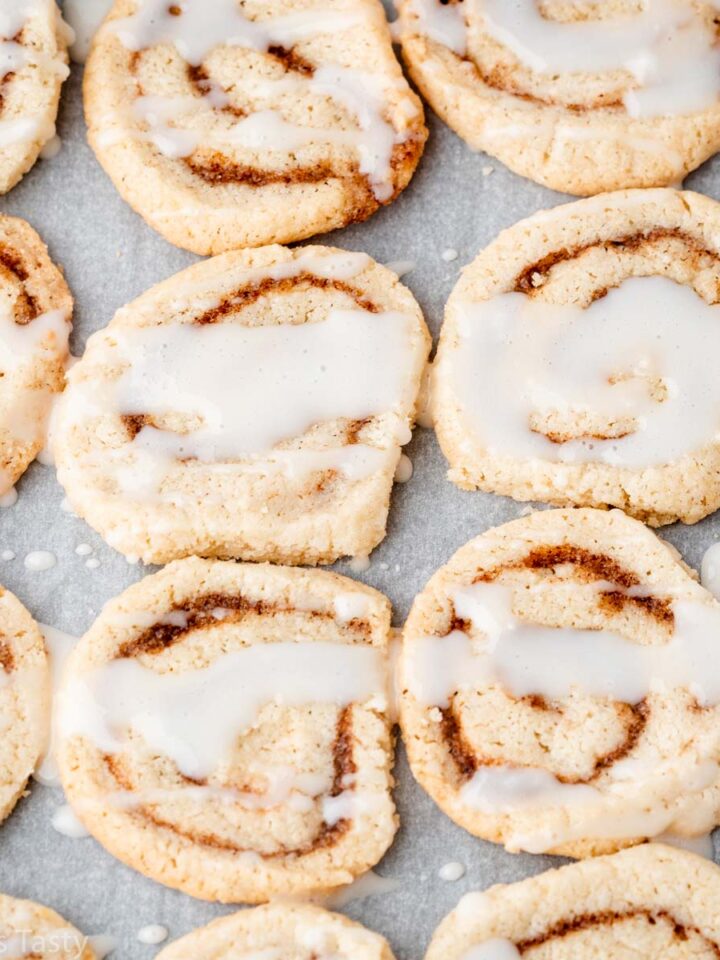 Glazed cinnamon roll cookies on parchment paper.